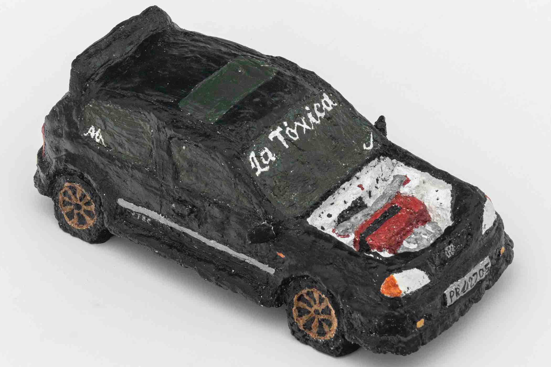 Black model car with visible painted engine in the hood and 'La Toxica' written on the windshield.