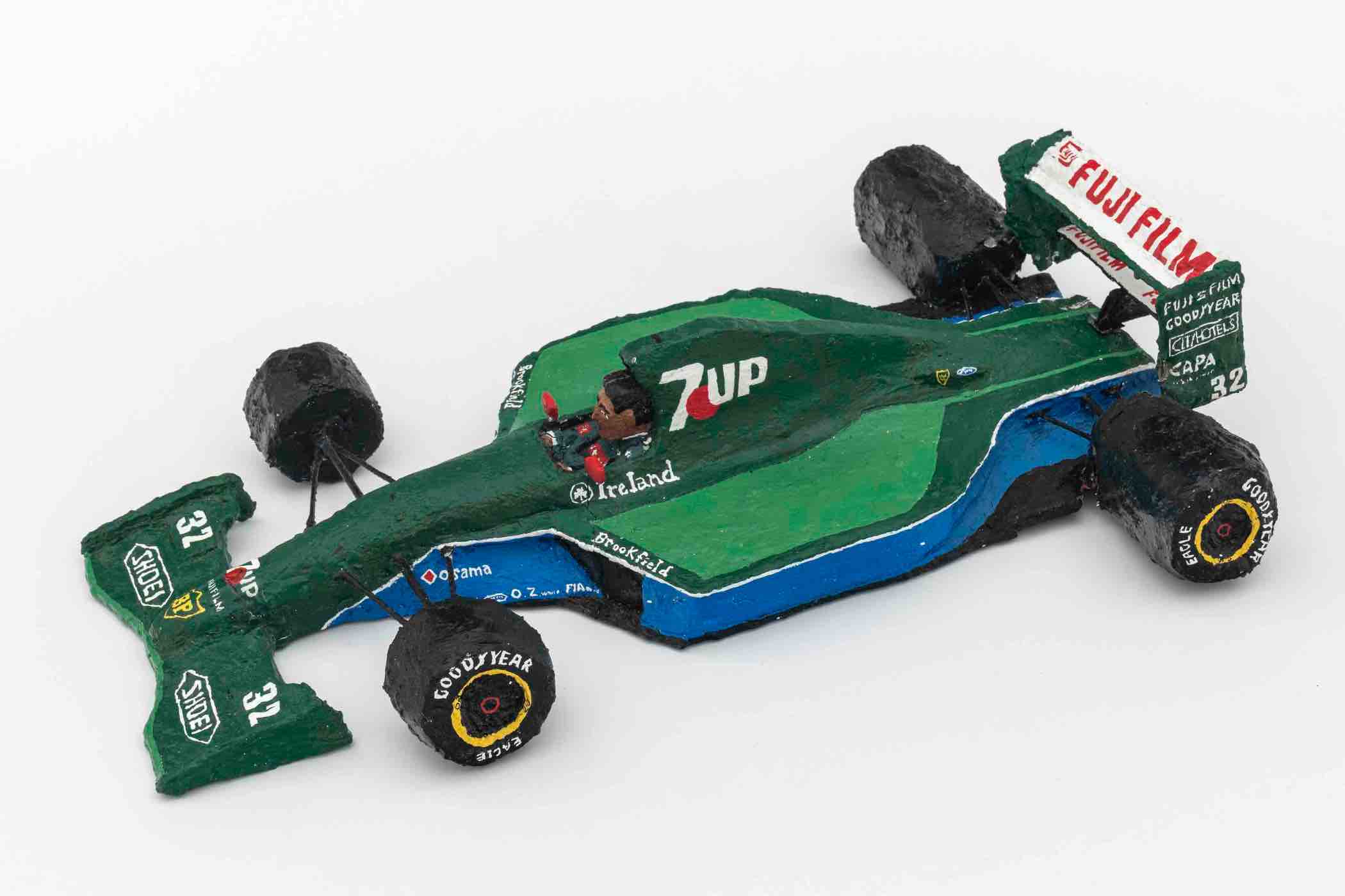 Hand-painted miniature model of a green Formula 1 race car with 7UP and Fujifilm logos and a driver figure inside.