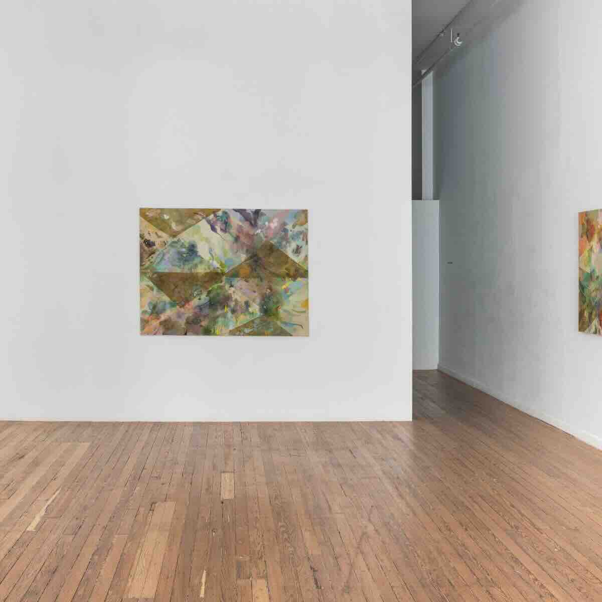 Interior of an art gallery with wooden floors, white walls, and two abstract paintings featuring mixed colors and geometric shapes displayed on the walls.