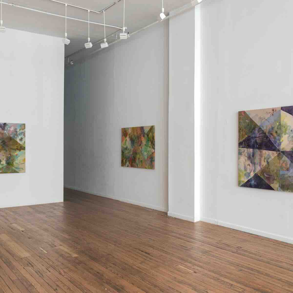 Interior view of an art gallery with wooden floors and white walls, featuring three abstract paintings with geometric and organic shapes in various colors.