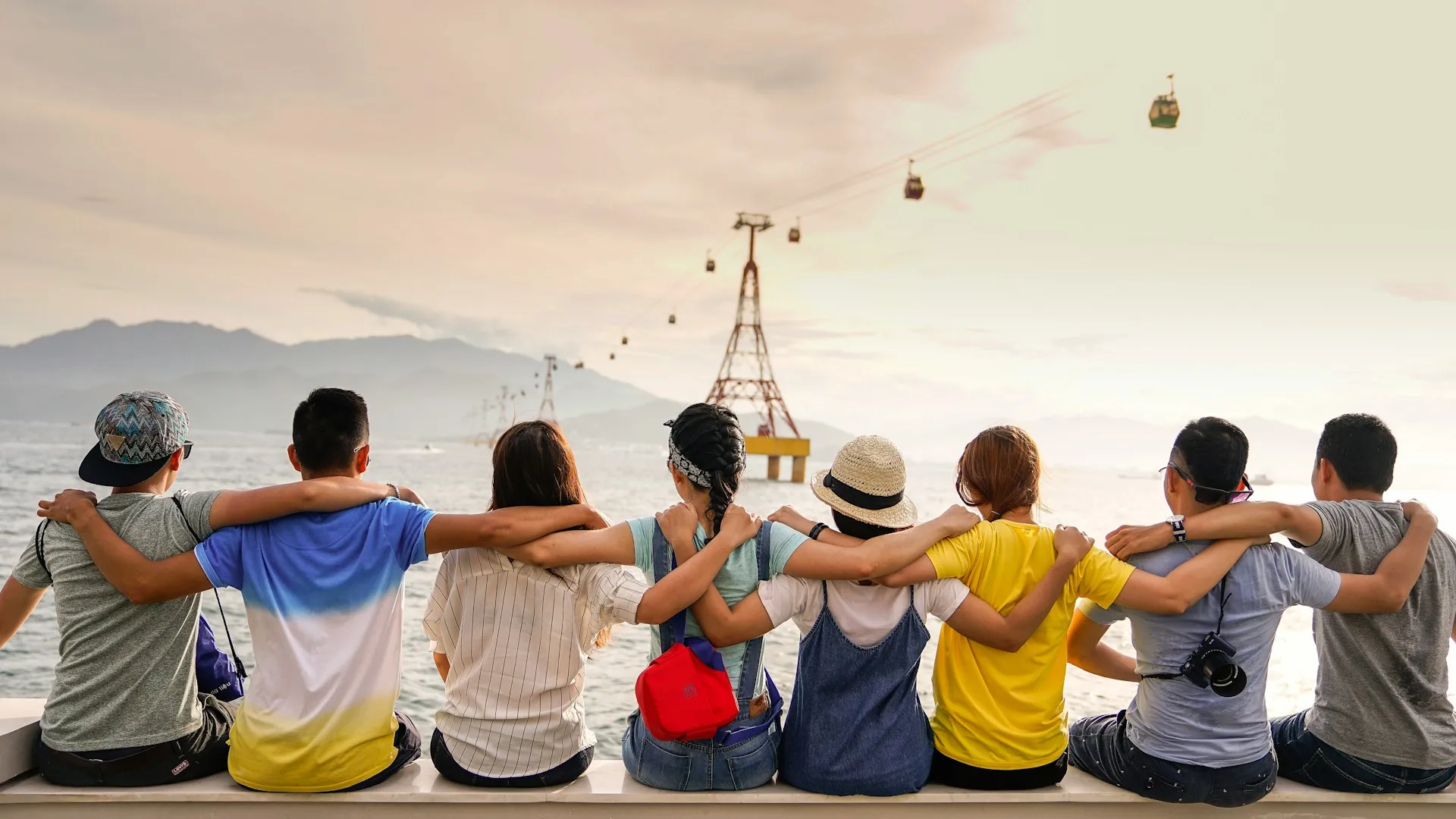 teenagers sitting on the beach looking at the sea