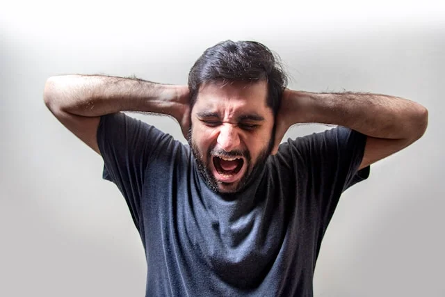 man with hands over his ears