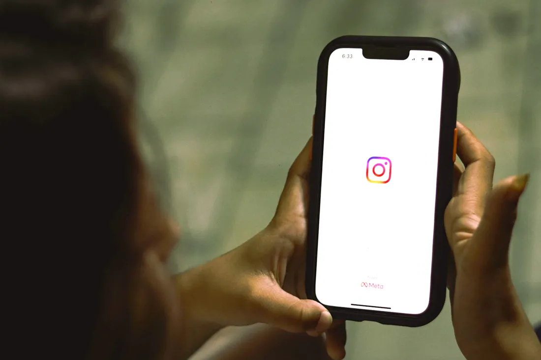 Person holding a phone showing the Instagram app loading screen with the Meta logo.