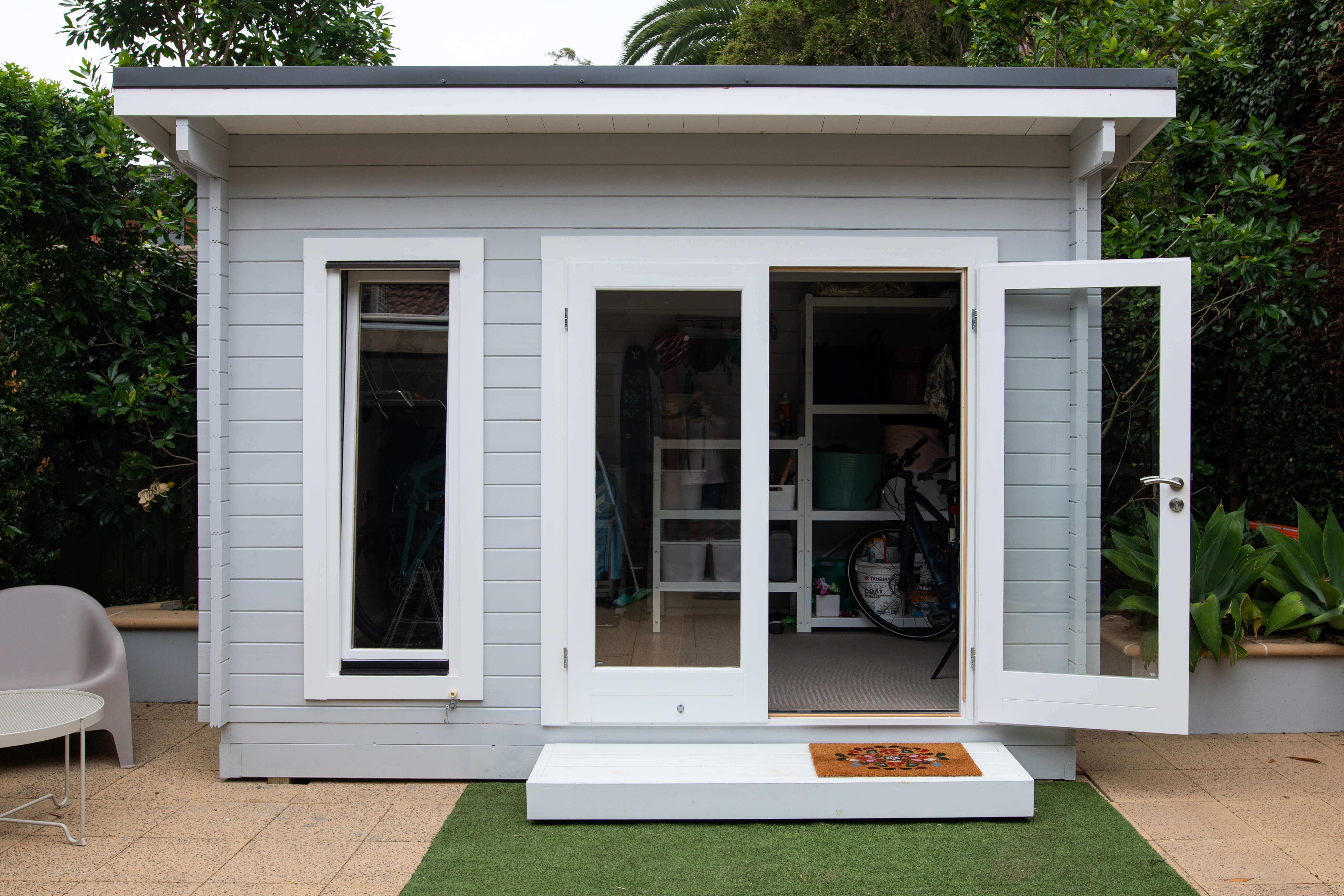 Rustic backyard shed converted into a functional ADU, featuring a pitched roof and outdoor seating area.