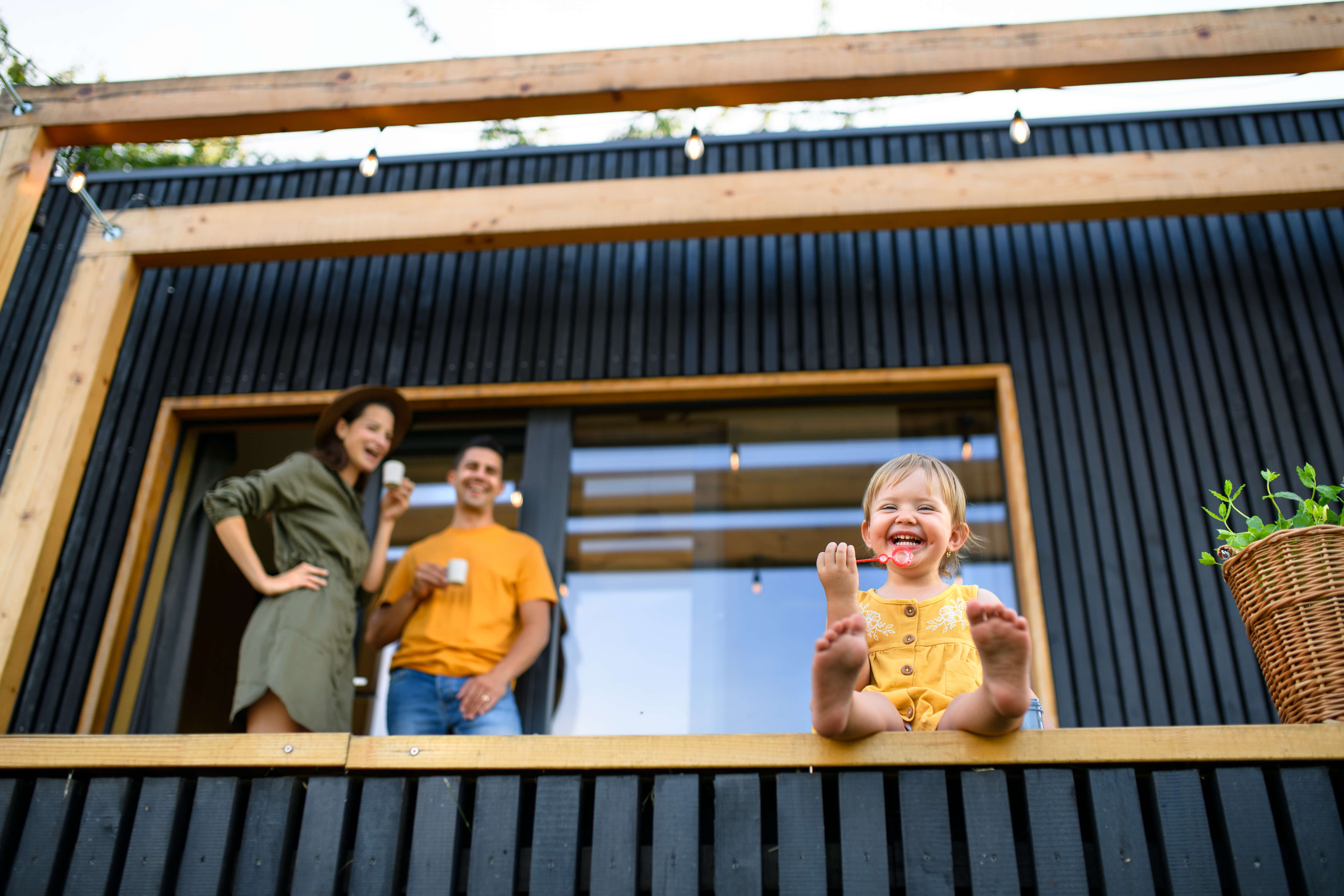 amily enjoying time on a modern black wood-clad ADU balcony, with string lights and warm outdoor ambiance.
