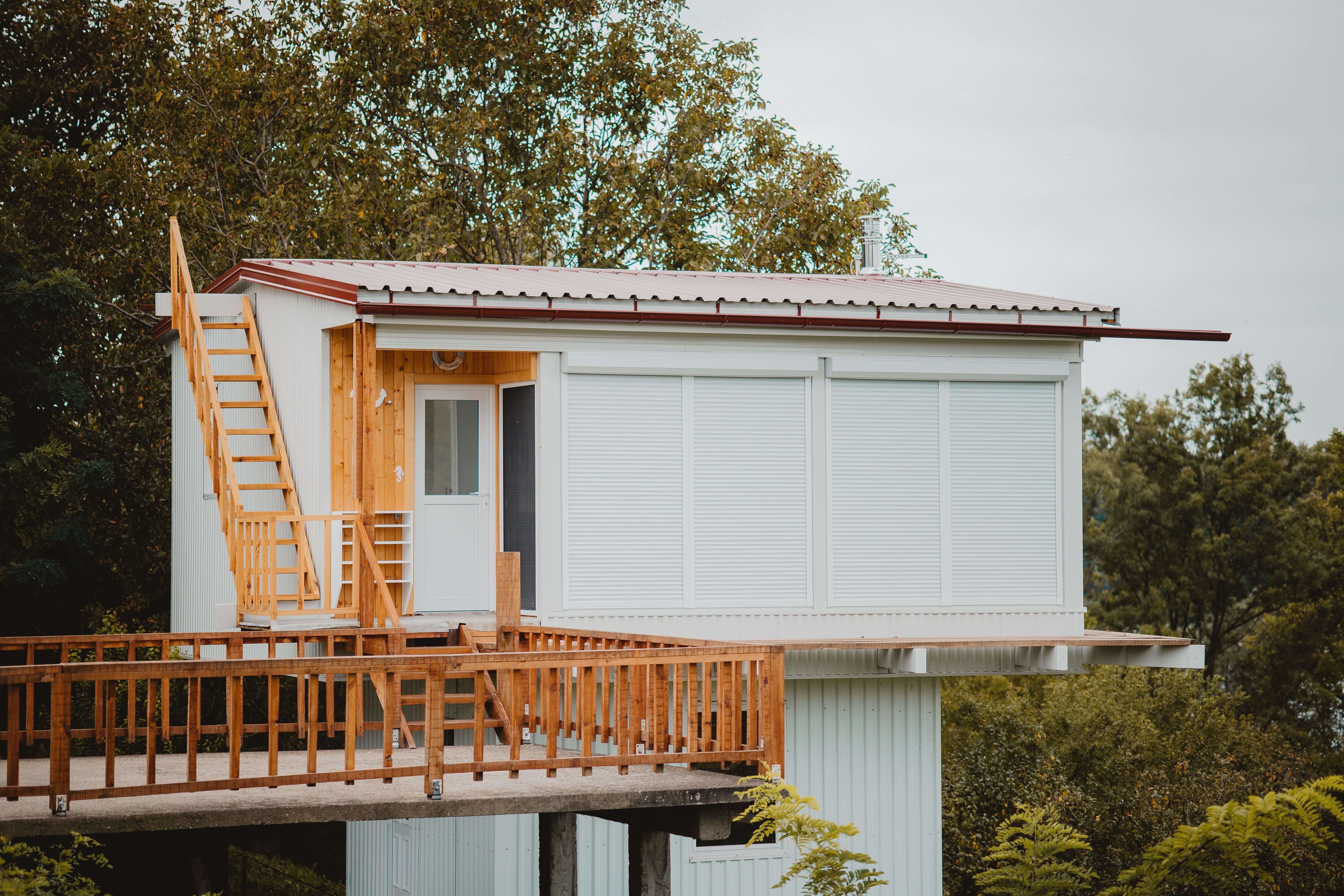Modern elevated ADU with wood accents, rooftop access, and wraparound deck surrounded by trees in a Denver backyard.