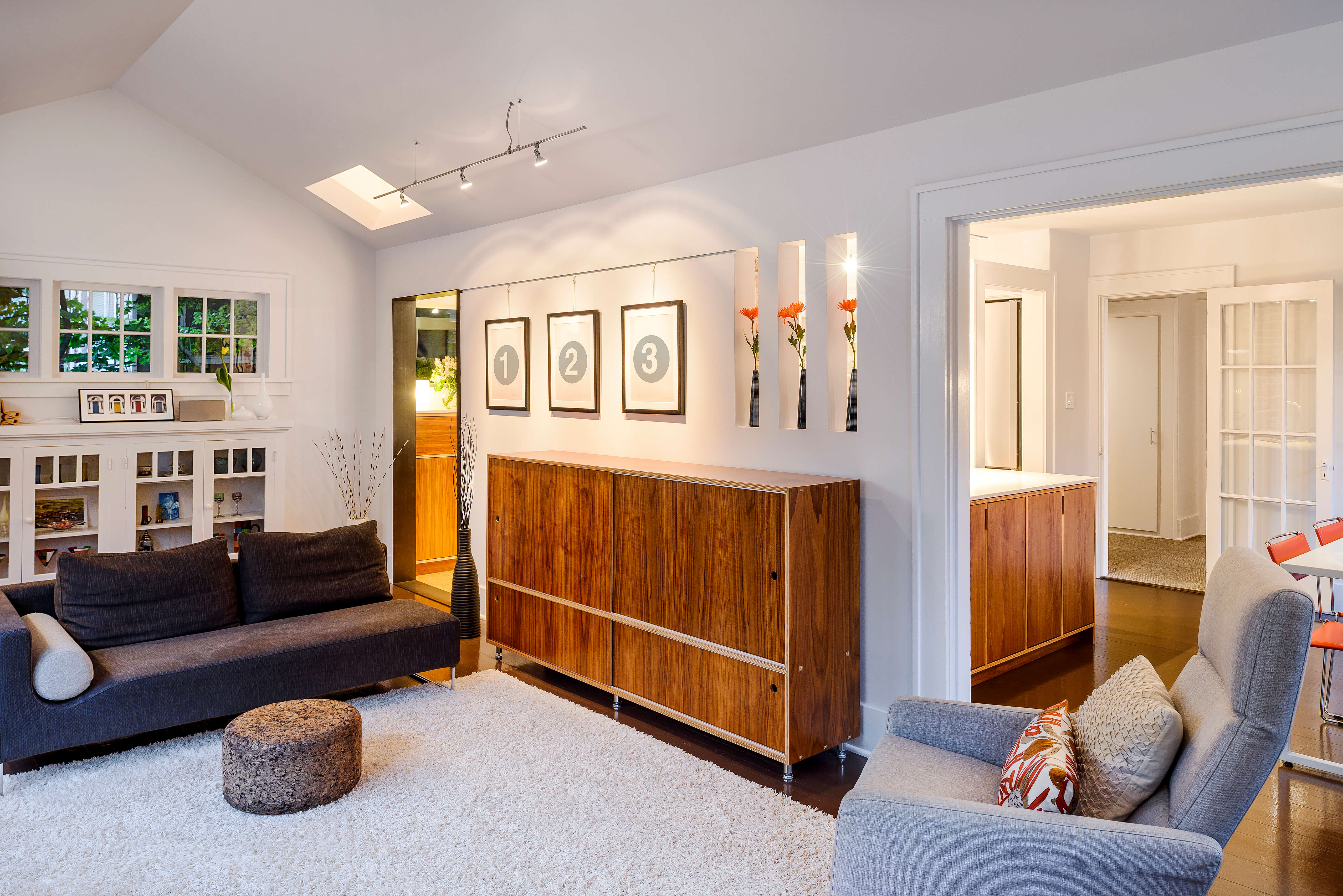 Modern ADU living room with wood cabinetry, cozy seating, and skylight windows, designed as a functional accessory dwelling unit.