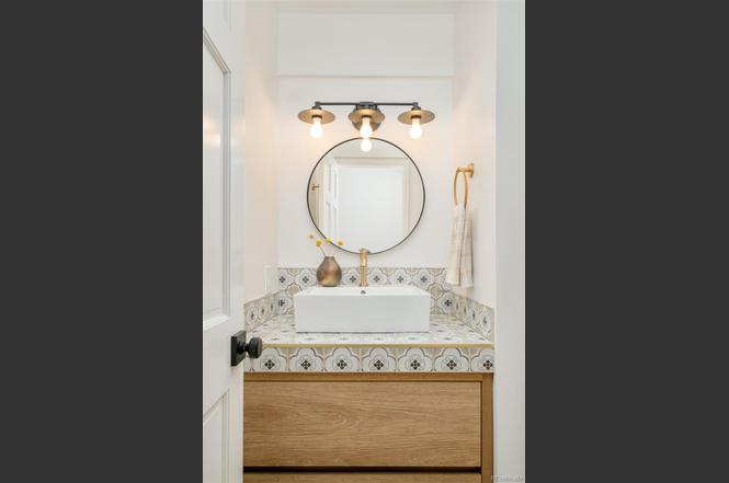 Bathroom remodel with patterned tile backsplash, round mirror, and modern lighting — showcasing detailed craftsmanship.