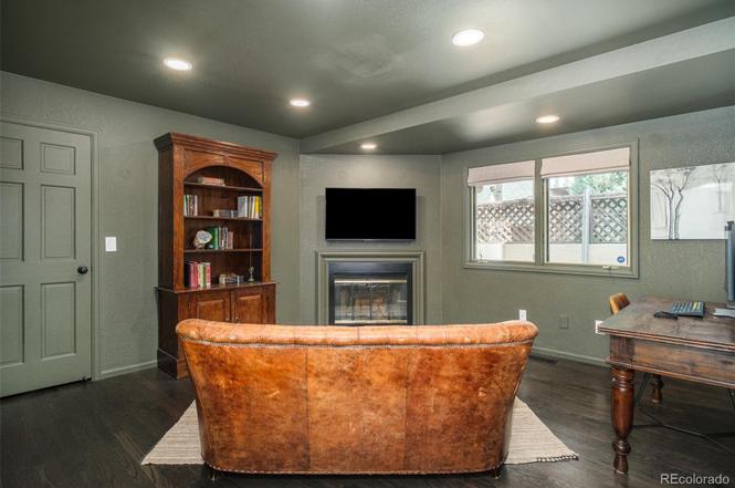 Cozy basement living area in a Hilltop Denver home remodel with leather seating, built-in shelving, and a fireplace.
