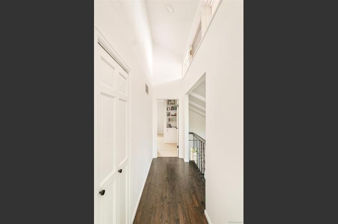 Hallway in a remodeled home featuring white walls, hardwood floors, and updated trim work.