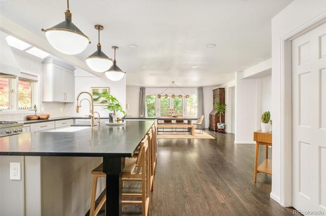 Spacious kitchen and dining area in a Hilltop Denver home remodel with wide-plank wood floors and warm lighting.