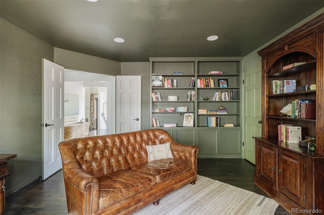 Cozy reading nook in a custom home remodel featuring built-in shelving, green cabinetry, and a vintage leather sofa.