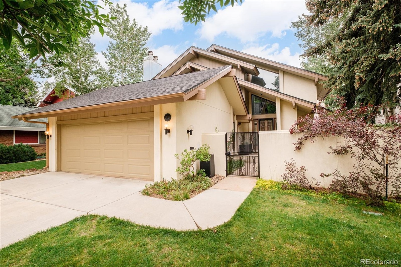Exterior view of a remodeled Hilltop Denver home featuring a two-car garage, beige stucco exterior, and landscaped driveway.