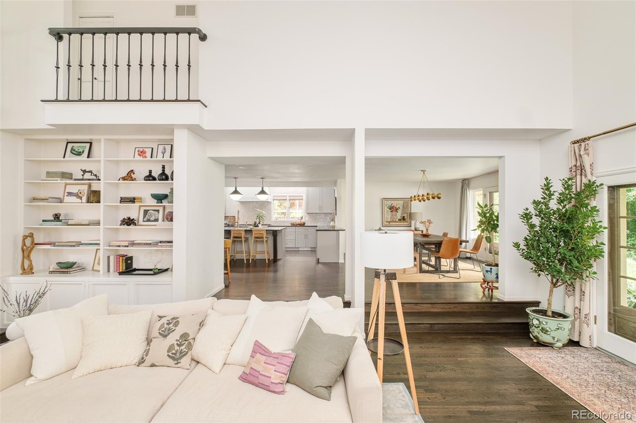 Open-concept living room and kitchen in a remodeled Hilltop Denver home with neutral tones and built-in shelving.