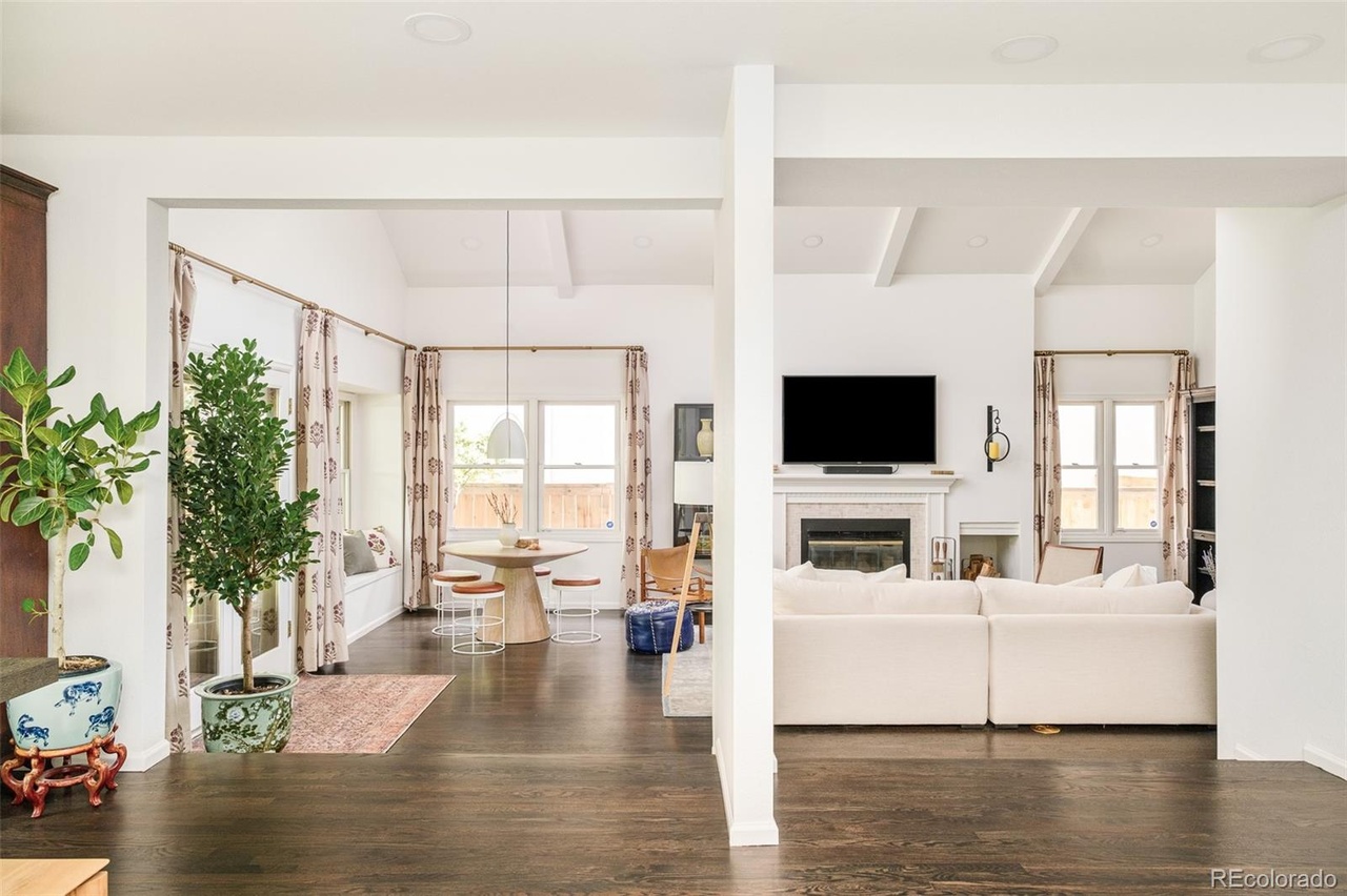 Open dining nook and living room in a remodeled Hilltop Denver home with wood floors, pendant lighting, and cozy natural tones.