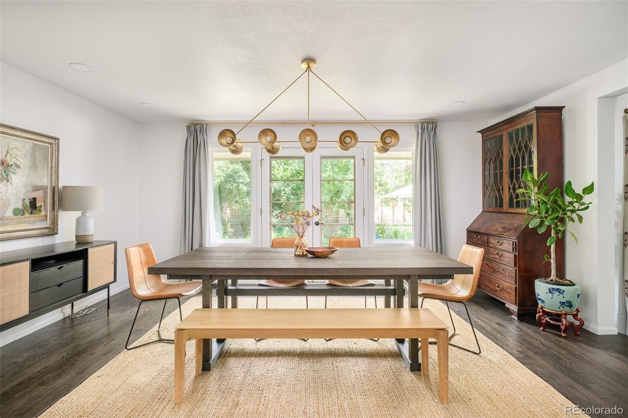 Dining room in a Hilltop Denver remodel with a wood table, modern lighting fixture, and natural light from French doors.