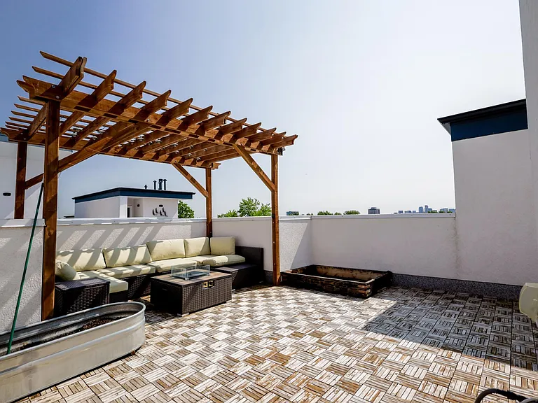 Outdoor terrace featuring a wooden pergola, built-in seating, and decorative tile floor