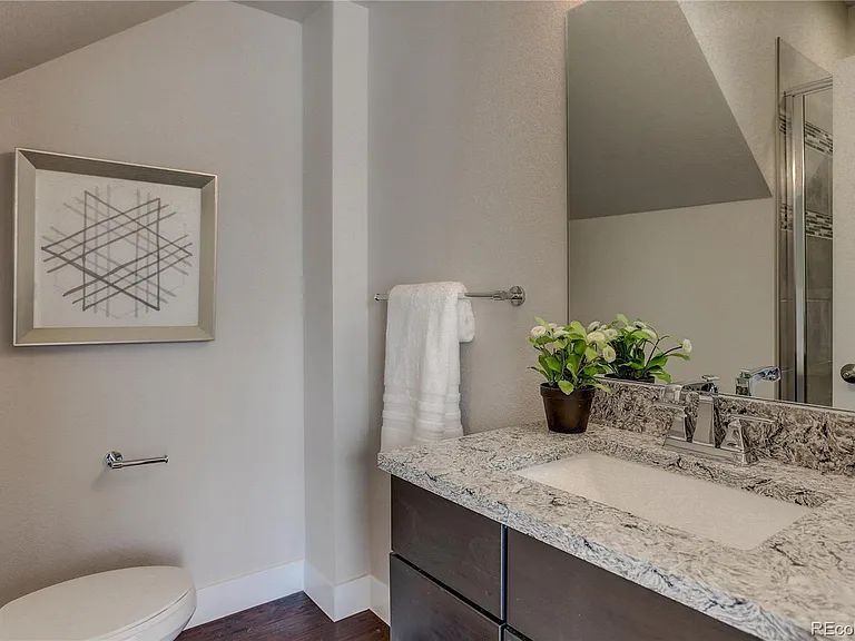 Powder room with framed art, marble countertop, and dark wood cabinetry