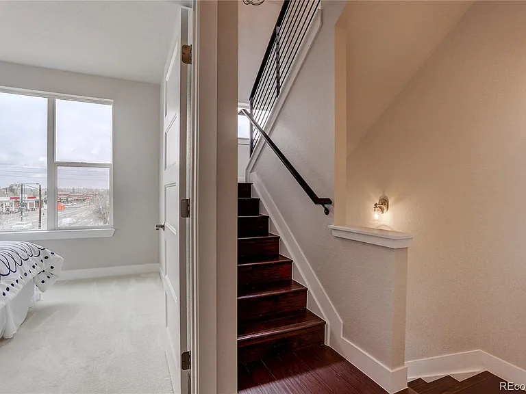 Carpeted staircase with white trim, wooden railing, and corner landing
