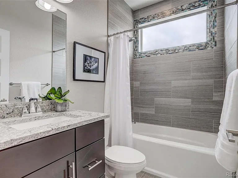 Full bathroom with modern tile surround, integrated shower curtain, and vanity with dual mirrors