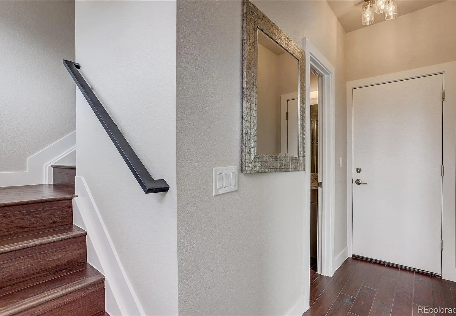 Entryway with warm lighting, hardwood floors, and stair access to upper level