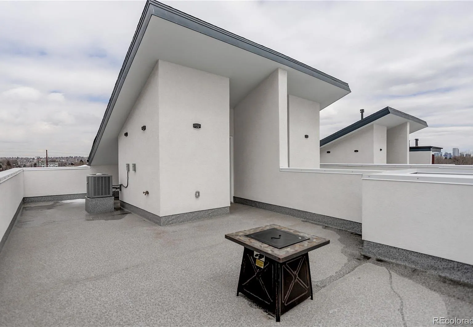 Rooftop patio with mountain views and stucco siding, ideal for outdoor lounging