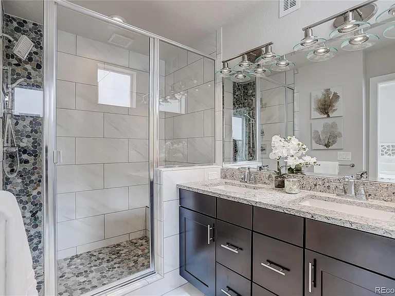 Luxurious bathroom with double vanity, glass shower enclosure, and marble tile accents