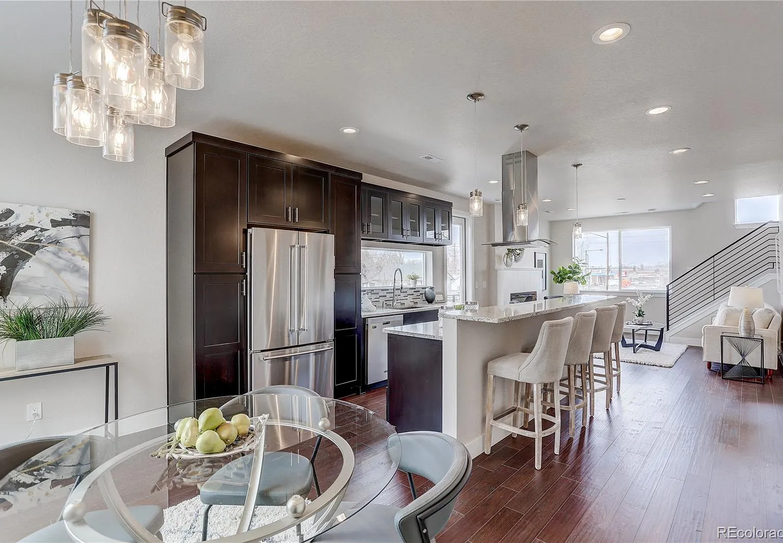 Wide view of kitchen and dining area with hardwood floors and recessed lighting
