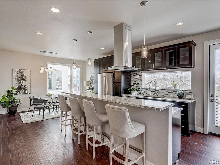 Spacious kitchen with oversized island, white quartz countertops, and bar seating under pendant lighting
