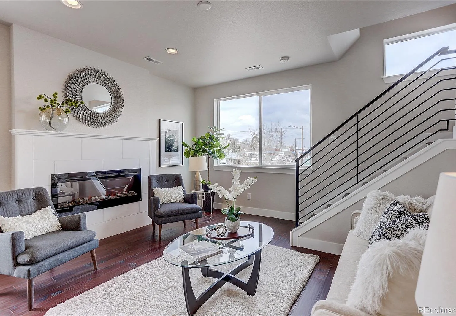 Cozy living room with accent chairs, neutral decor, and large windows for natural light