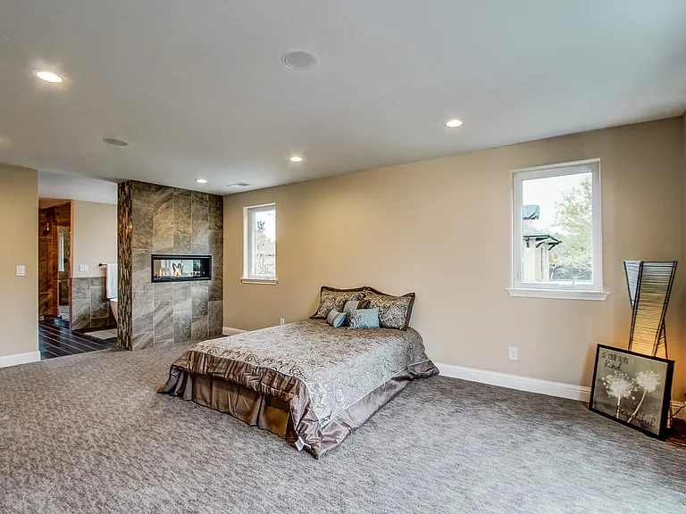 Spacious primary bedroom with neutral carpeting, recessed lighting, and a large window for natural light