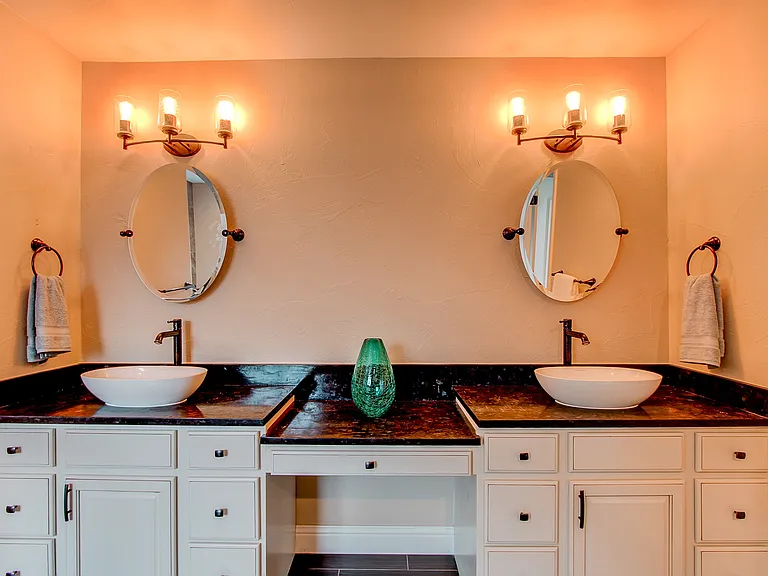 Double vanity bathroom with two vessel sinks, elegant lighting fixtures, and large framed mirrors