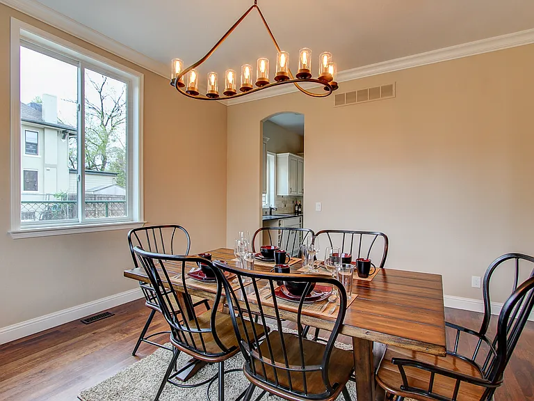 Bright and inviting dining room with hardwood floors, traditional chandelier, and oversized window