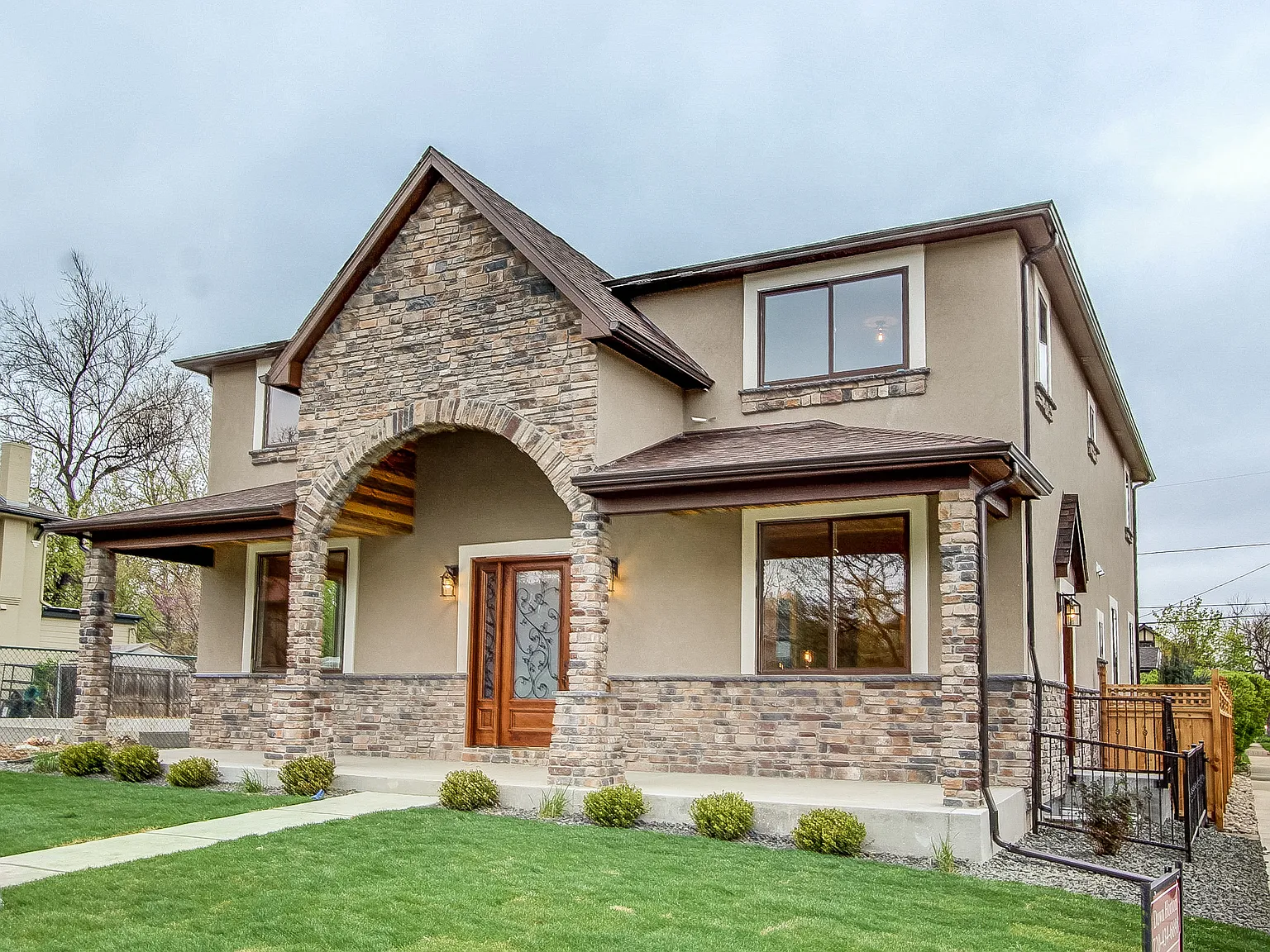 Exterior view of a custom-built Denver home featuring stonework, stucco, and a welcoming arched entry