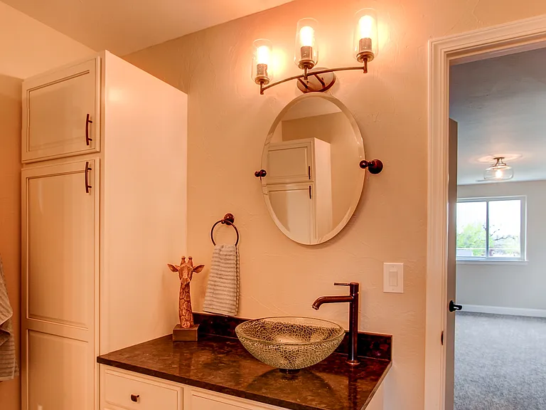 Elegant bathroom vanity with dark granite top, vessel sink, and modern lighting above mirror