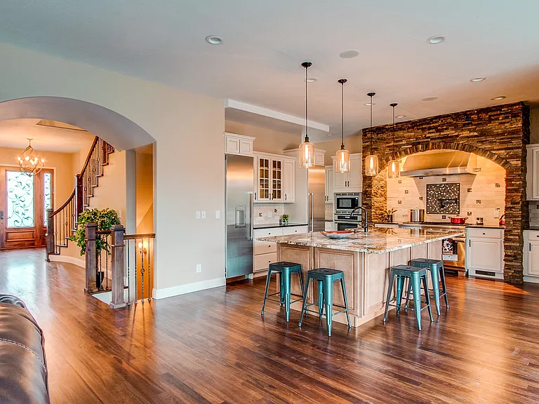 Expansive open kitchen and living area with large island, pendant lighting, and stone backsplash