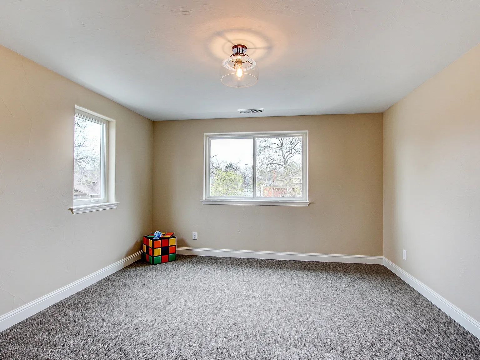 Cozy upstairs bedroom with neutral walls, new carpeting, and dual windows for natural light