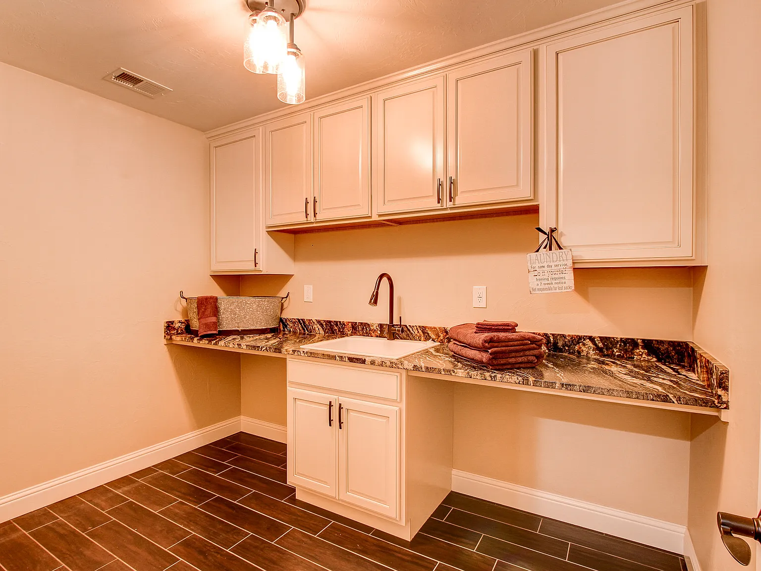 Functional mudroom or laundry space with built-in cabinetry, granite countertops, and tile flooring