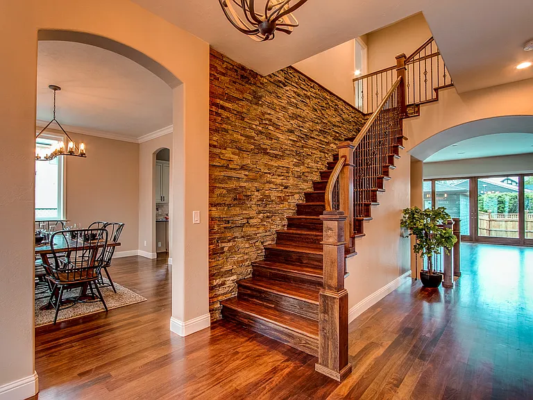 Elegant entryway with hardwood floors, curved archway, and a striking stone accent staircase wall