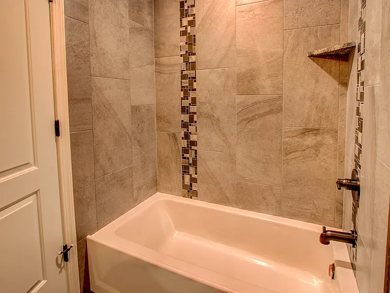 Contemporary bathtub and shower combo with full tile surround and mosaic accent strip