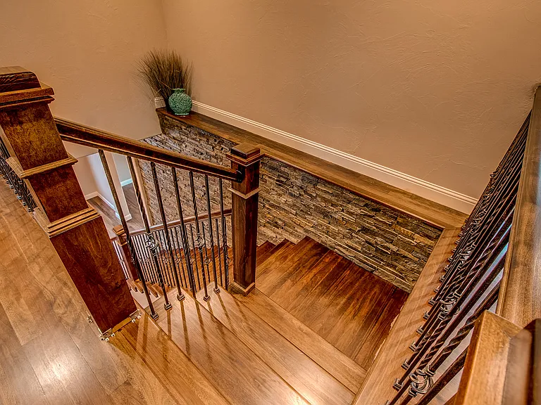 Overhead view of a hardwood staircase with decorative railing and a cozy runner accent