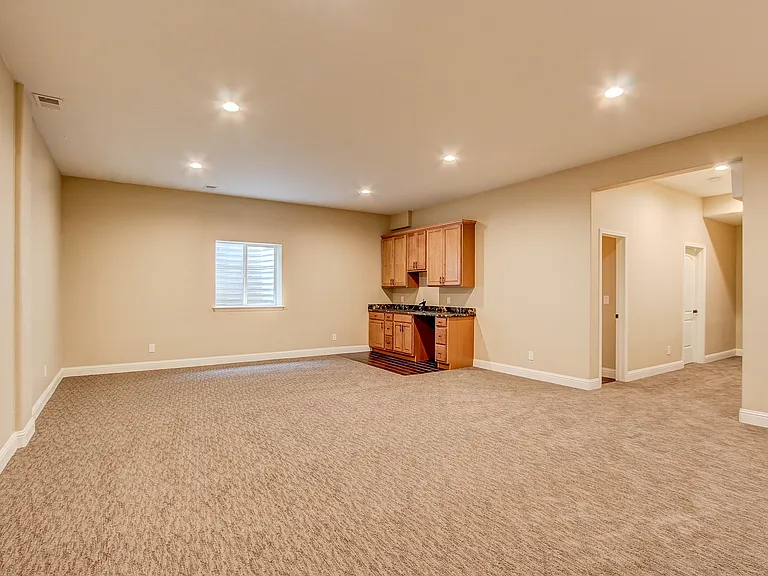 Spacious finished basement featuring plush carpeting, built-in cabinetry, and recessed lighting