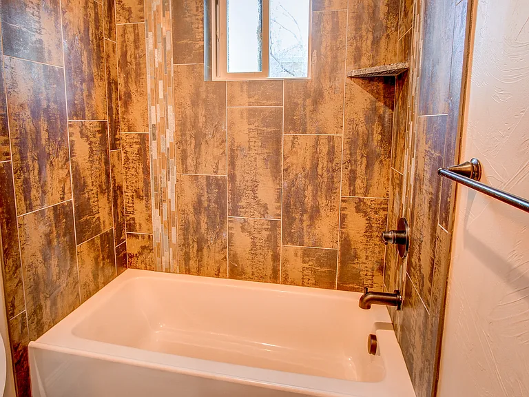 Rustic-inspired bathroom with deep soaking tub and full-height textured tile surround