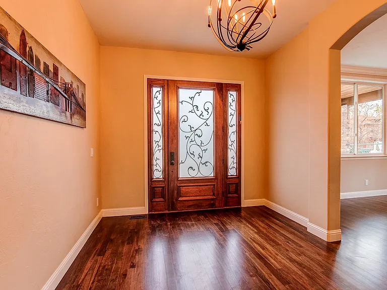 Welcoming front foyer with hardwood flooring, elegant chandelier, and custom glass-paneled door
