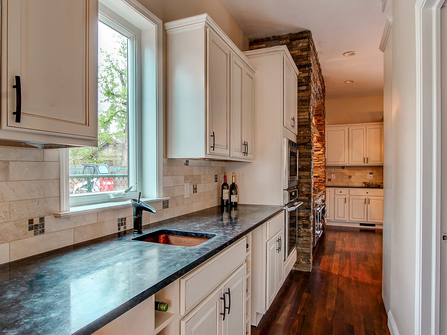Galley-style kitchen with black granite countertops, white shaker cabinets, and stainless steel fixtures