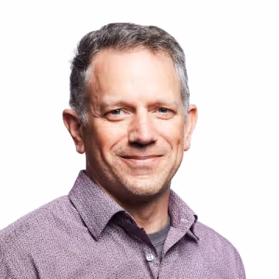 Headshot of Evan Driscoll, VP of Engineering at Augment, wearing a collared shirt and smiling.