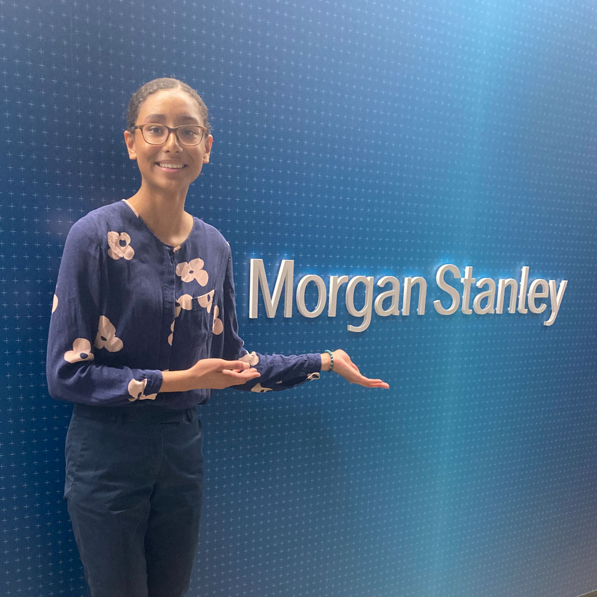 A Futures and Options student poses in front of the Morgan Stanley logo