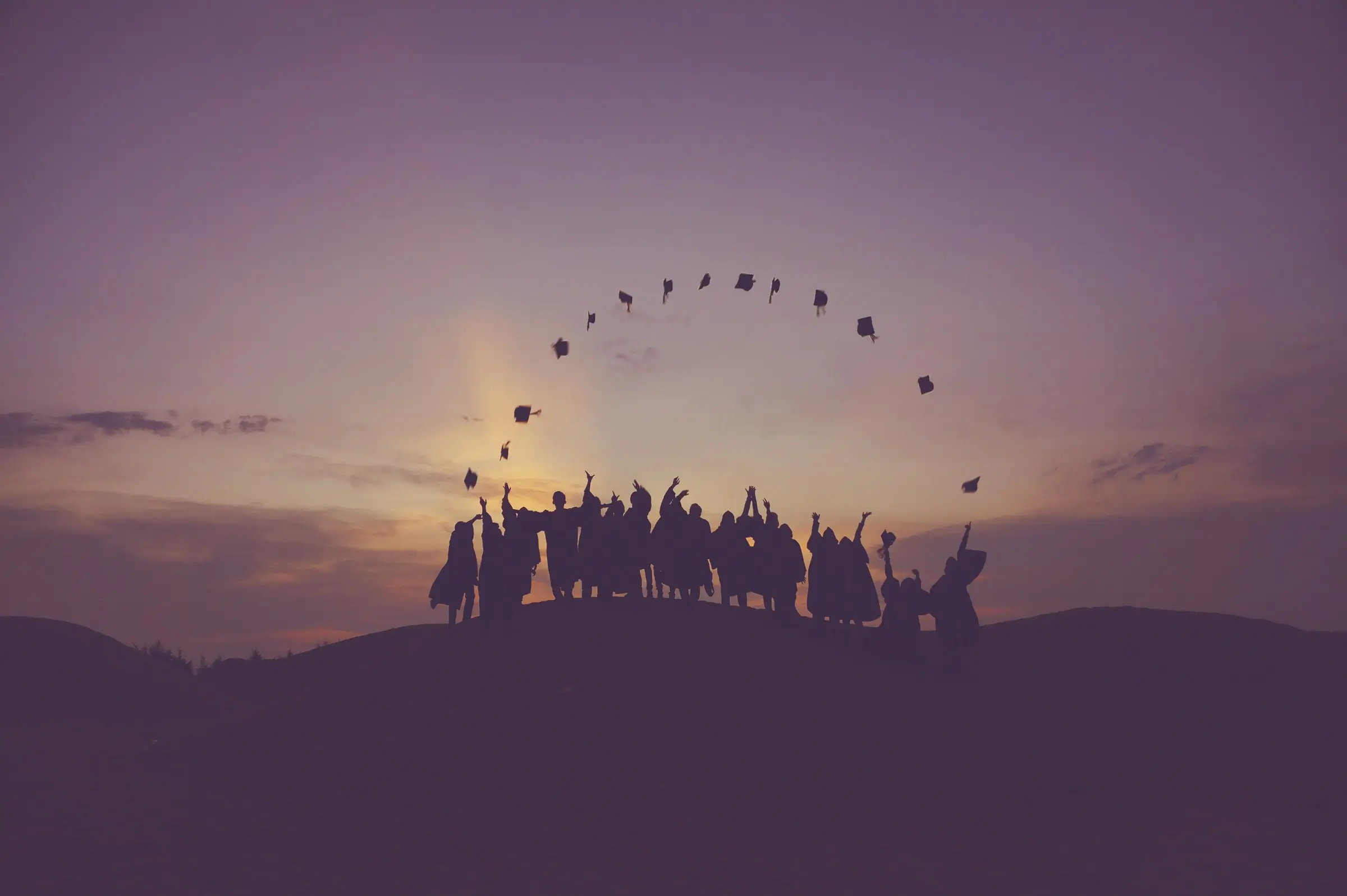 Graduates tossing their caps into the air at sunset