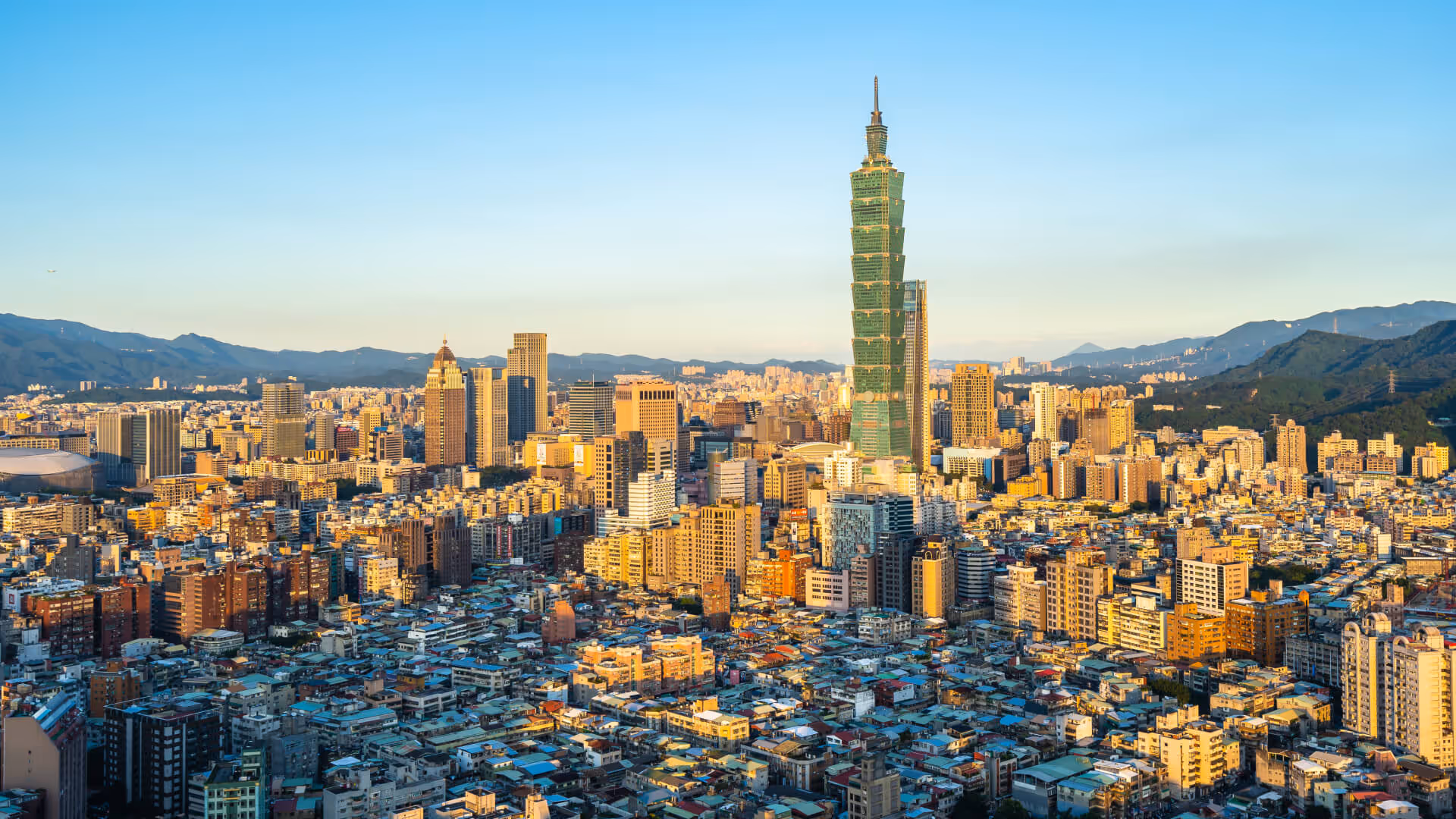 Cityscape of Taipei with Taipei 101 skyscraper standing prominently against a clear blue sky.