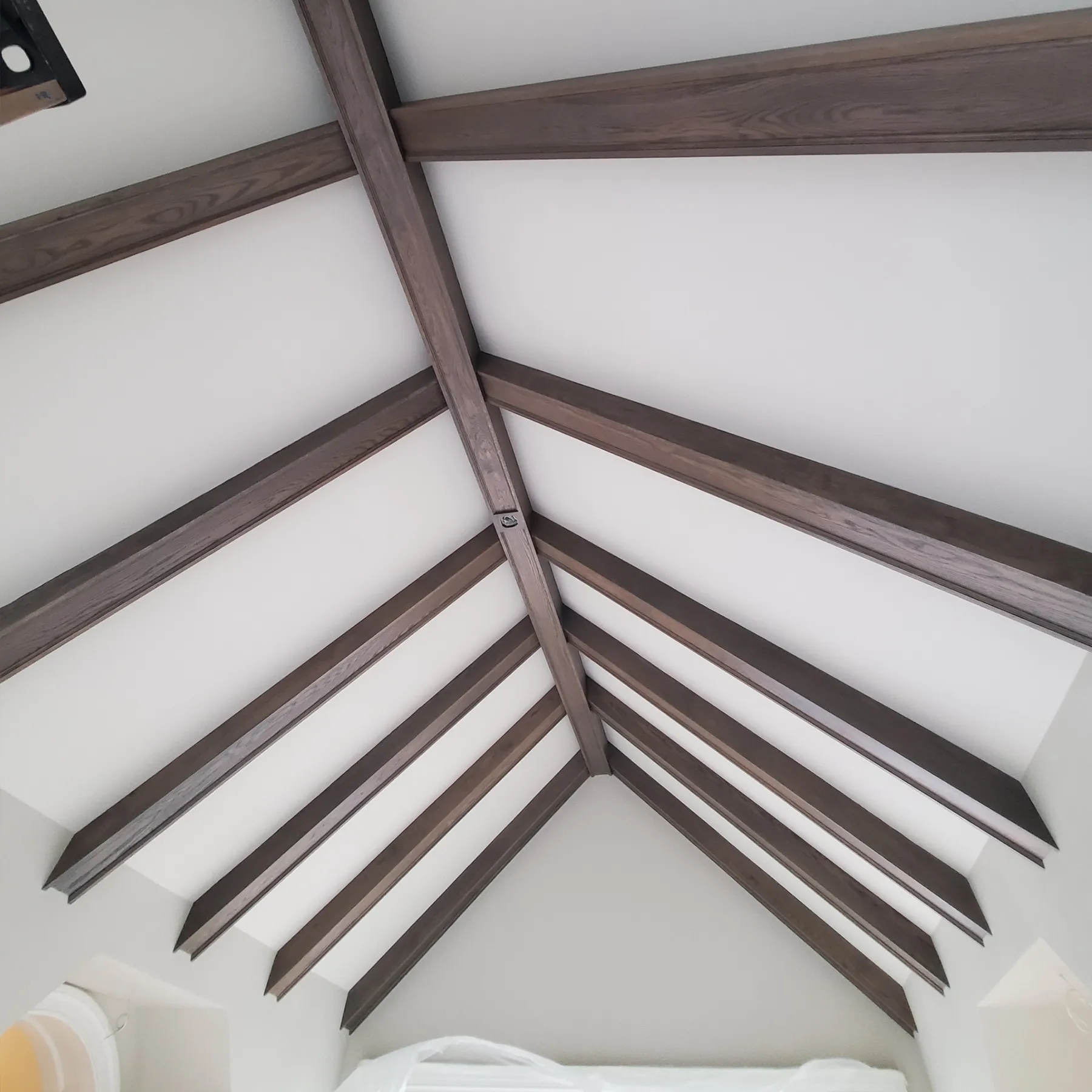 Vaulted ceiling with stained dark walnut wooden beams in a crisscross pattern, installed by Chris Painting and Remodeling.